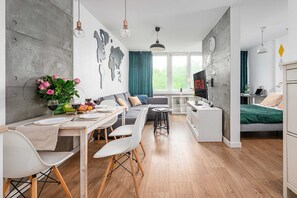 A modern living space with a dining area, a sofa, a TV, and a bed. - Sunlit Home with City Views (Warszawa)