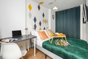 Quarto moderno com cama, escrivaninha e uma cesta de frutas.