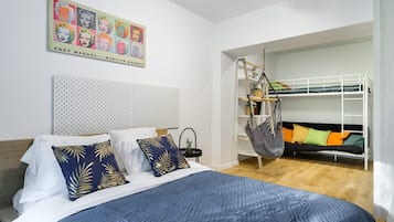 A bedroom with a bunk bed, a hanging chair, a bed with patterned pillows, a headboard with a perforated design, and a wall art piece.