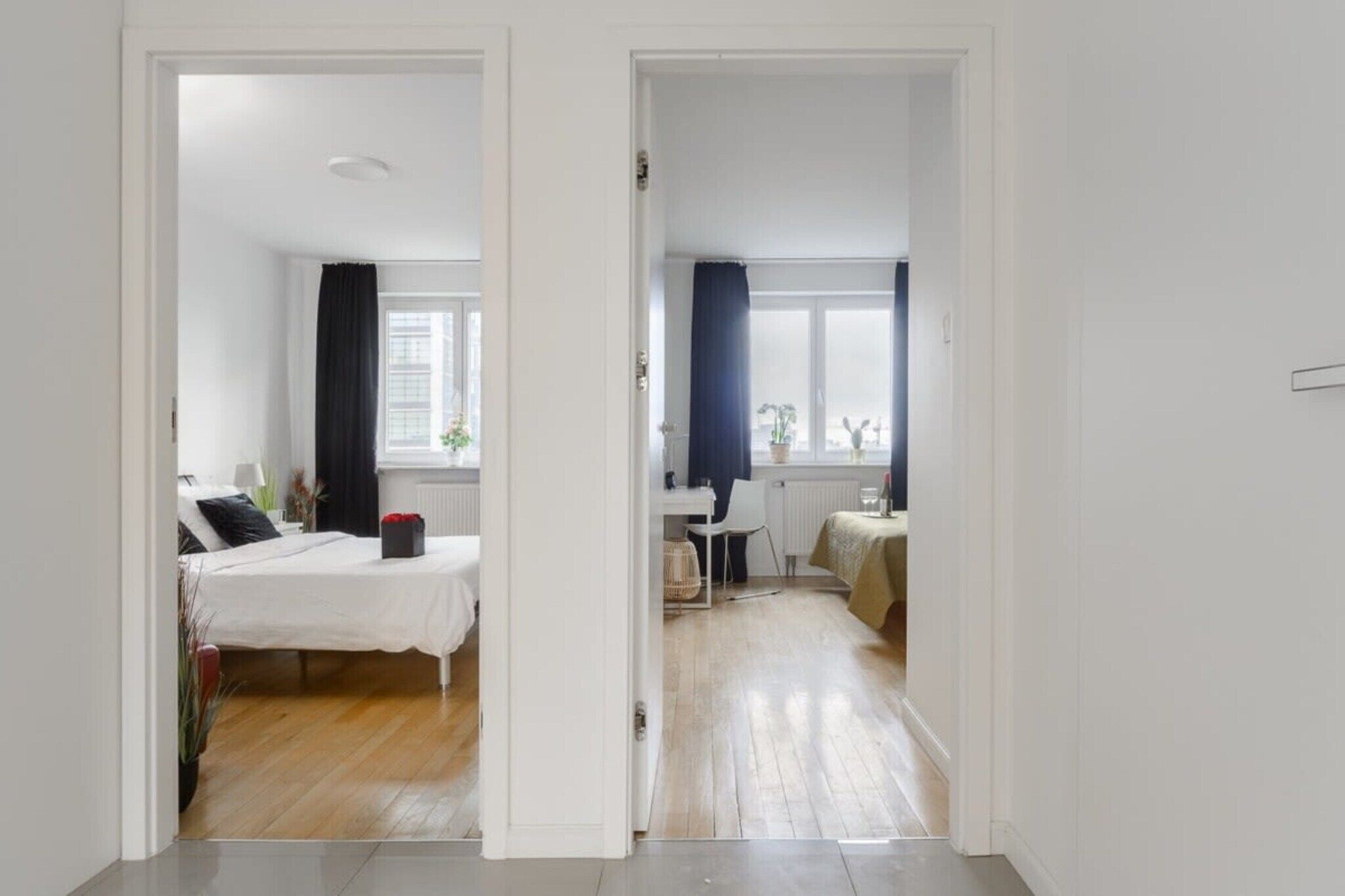 Quarto com cama, escrivaninha e cadeira. Há uma janela com cortinas.