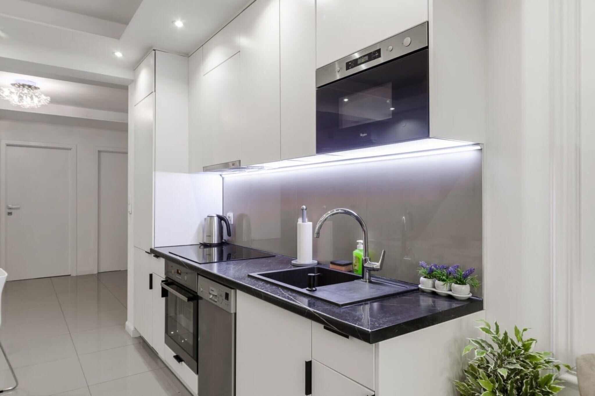Uma cozinha moderna com eletrodomésticos de aço inoxidável, bancada preta e forno embutido.
