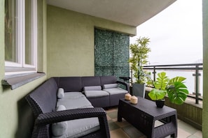 A balcony with a grey sofa, a small table, and potted plants.