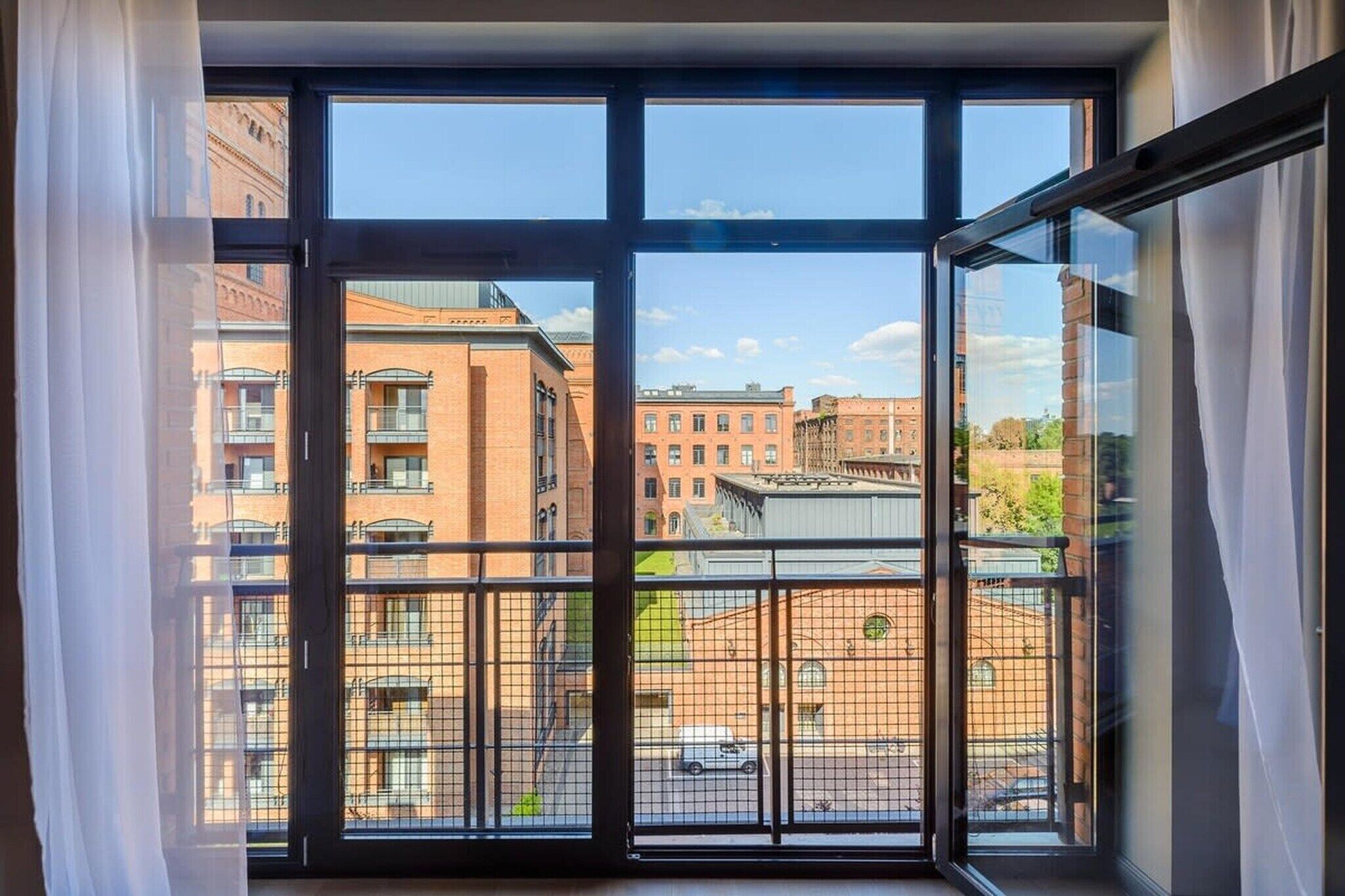 Finestra amb vista a un paisatge urbà, amb edificis i un carrer.