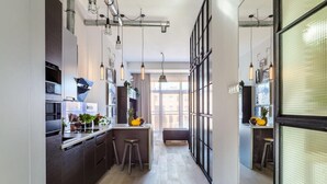 A modern kitchen with a central island, pendant lighting, and a view to the living area. - Loft Flat in Historical Area (Łódź)