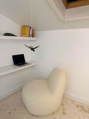 A room with a white chair, a laptop on a shelf, and a hanging bird decoration. - Lila Loft Bordeaux - Air-Conditioned Apartment in the Heart of the City Center (Bordeaux)