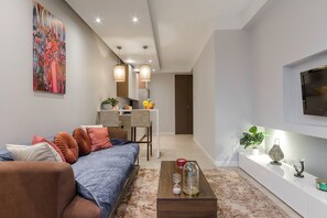 Ein modernes Wohnzimmer mit einer Couch, einem Couchtisch und einem an der Wand befestigten Fernseher.