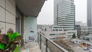 Ein Balkon mit einer Hängematte, Blick auf eine Stadtlandschaft mit modernen Gebäuden und einer Straße darunter.