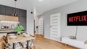 Een moderne keuken met een eetgedeelte, een flatscreen televisie aan de wand en een minimalistisch design.