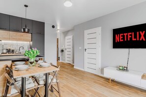 Eine moderne Küche mit Essbereich, einem an der Wand befestigten Flachbildfernseher und einem minimalistischen Design.