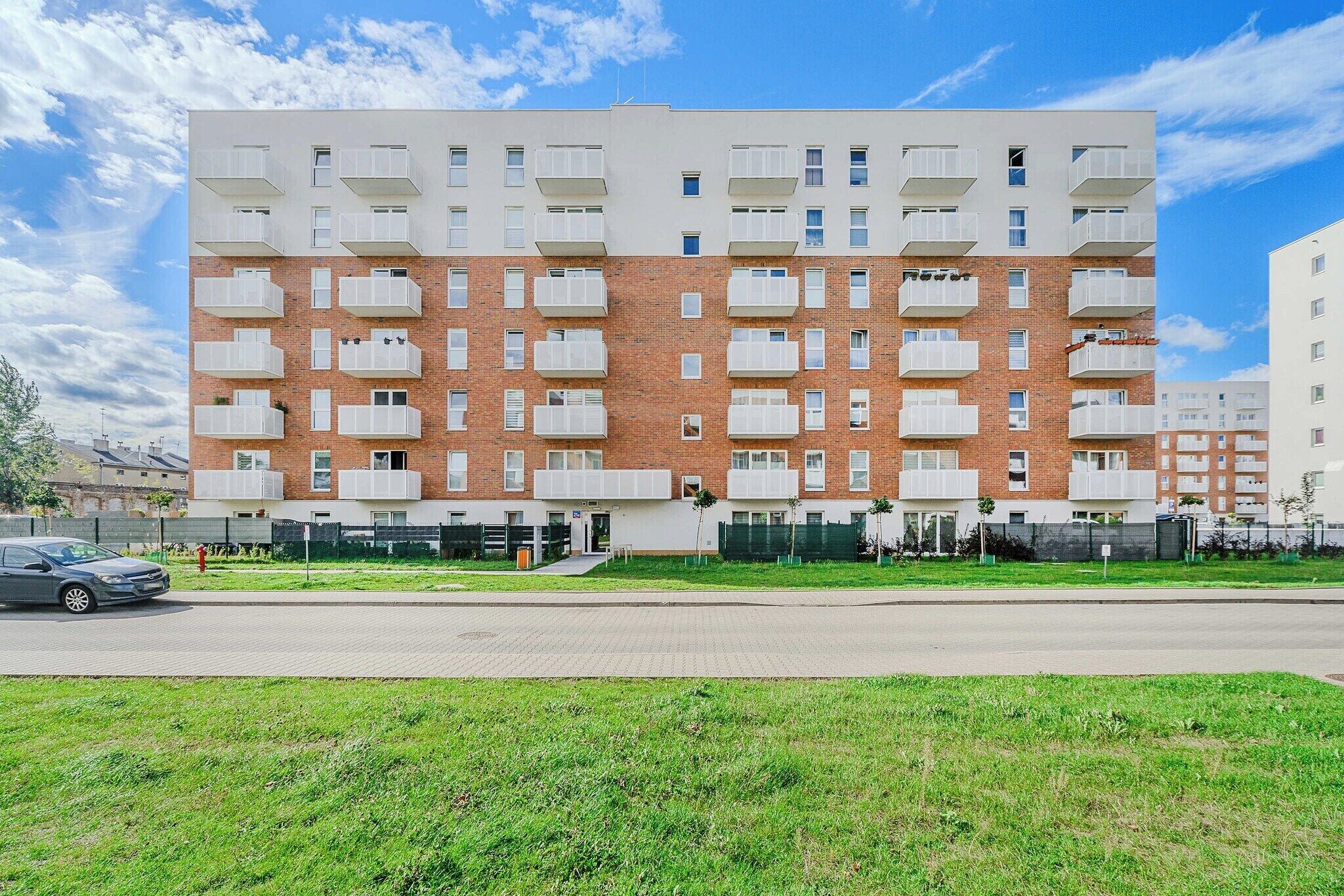 A multi-story residential building with a brick facade and white balconies.