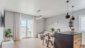Een moderne keuken met een centraal eiland, een eethoek en een groot raam met gordijnen.