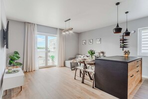 Eine moderne Küche mit Kochinsel, Essbereich und einem großen Fenster mit Vorhängen.