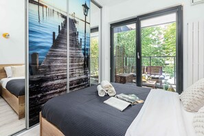 A bedroom with a large bed, a view of a wooden pier through a glass wall, and a balcony with outdoor furniture. - Warsaw Flat with City Views (Warszawa 2)