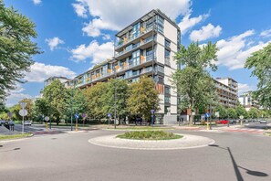 A modern multi-story building with balconies, a roundabout, and surrounding greenery. - Warsaw Flat with City Views (Warszawa 2)