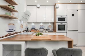 A modern kitchen with white cabinets, a wooden island, and a built-in oven. - Warsaw Flat with City Views (Warszawa 2)