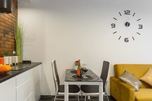 Eine moderne Küche mit Esstisch für zwei Personen, einem gelben Sofa und einer Wanduhr.