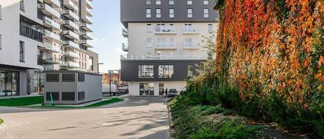 Un edificio moderno con varios pisos, un área de estacionamiento y un camino que lleva a la entrada.