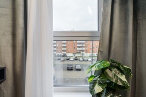 Ett fönster med utsikt över en parkeringsplats och en byggnad med flera våningar.