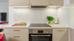 Eine moderne Küche mit eingebautem Ofen, einer Arbeitsplatte mit Schneidebrett und Gemüse sowie einer Wandpflanze.