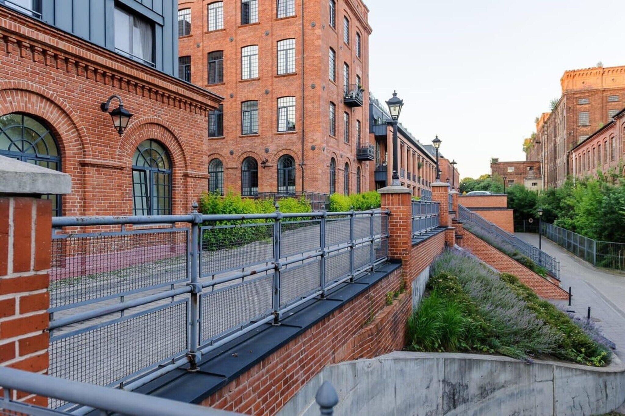 A brick building with a metal fence and a staircase leading to a lower level.