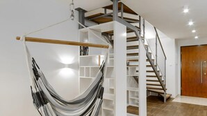 Un interior moderno con una hamaca, una escalera de caracol y una puerta de madera.