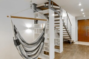 Ein modernes Interieur mit einer Hängematte, einer Wendeltreppe und einer Holztür.