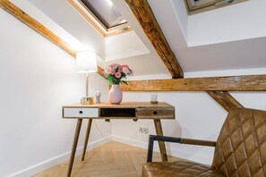 Quarto com escrivaninha, cadeira e claraboia.