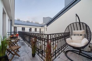 Varanda com mesa de jantar, cadeiras, cadeira suspensa e plantas em vasos.
