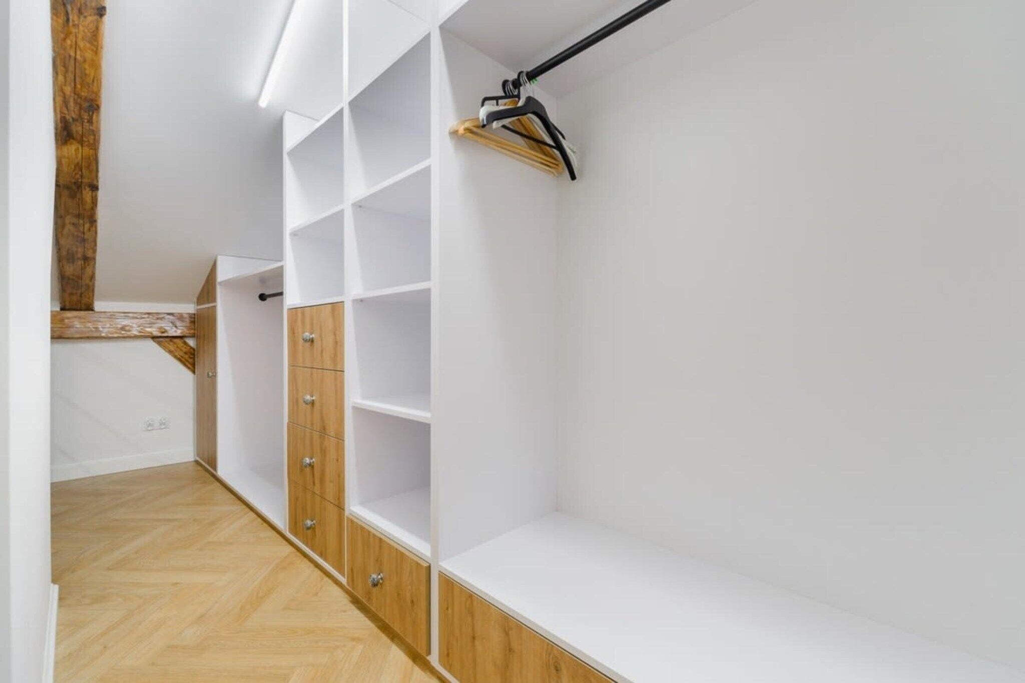 Een inloopkast met houten kastjes en open planken.