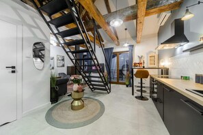 Eine moderne Küche mit einer zentralen Kochinsel, einer Treppe und einem Essbereich.