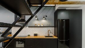 A modern kitchen with black cabinetry, a stainless steel refrigerator, and a wooden countertop. - Duplex Home near Manufaktura (Łódź)