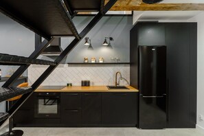 Eine moderne Küche mit schwarzen Schränken, einem Edelstahlkühlschrank und einer Holz Arbeitsplatte.