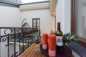 Ein Balkon mit Tisch für zwei Personen, komplett mit einer Weinflasche, zwei Gläsern und zwei Kerzen.