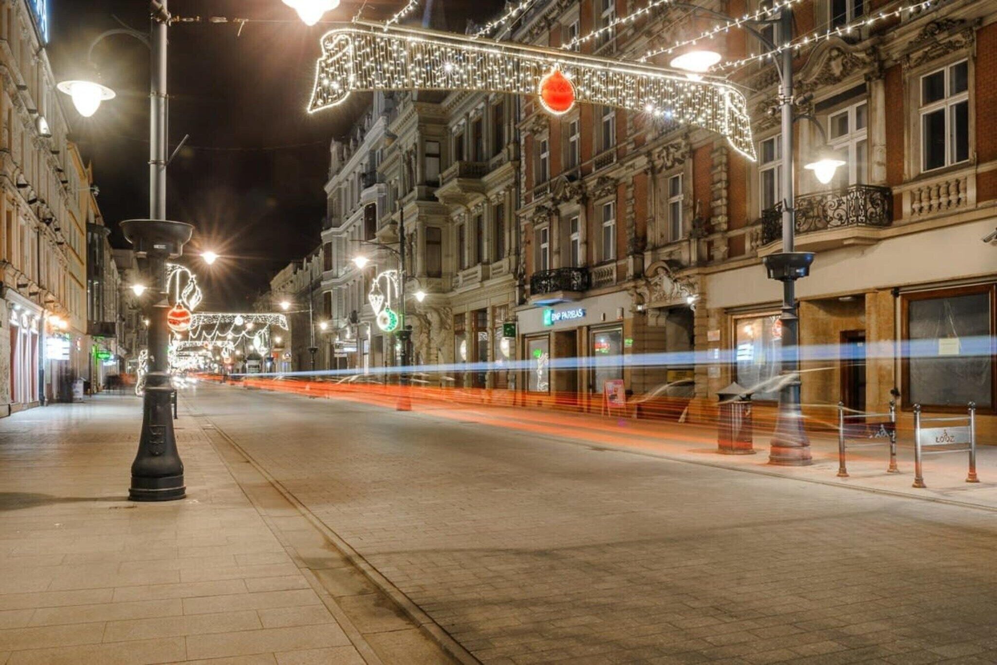 Eine beleuchtete Straße bei Nacht mit festlicher Dekoration und Gebäuden.