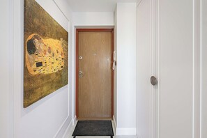A hallway with a wooden door, a doormat, and a large painting on the wall. - Family Stay in Warsaw (Warszawa 2)