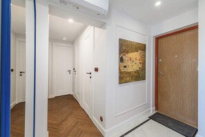 A hallway with white walls, a wooden floor, and a door with a brass handle. - Family Stay in Warsaw (Warszawa 2)