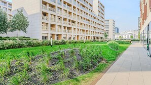 Ein modernes, mehrgeschossiges Gebäude mit flachem Dach und einem gepflegten Garten mit Gras und Sträuchern.