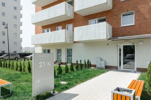 A residential building with balconies, a sign indicating unit 21 N, and a small garden area with benches. - 3-Bedroom Łódź Apartment with Balcony (Łódź)