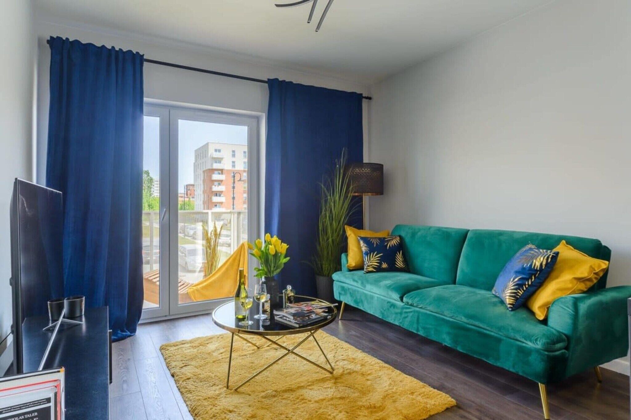 A modern living room with a green sofa, a coffee table, and a TV.
