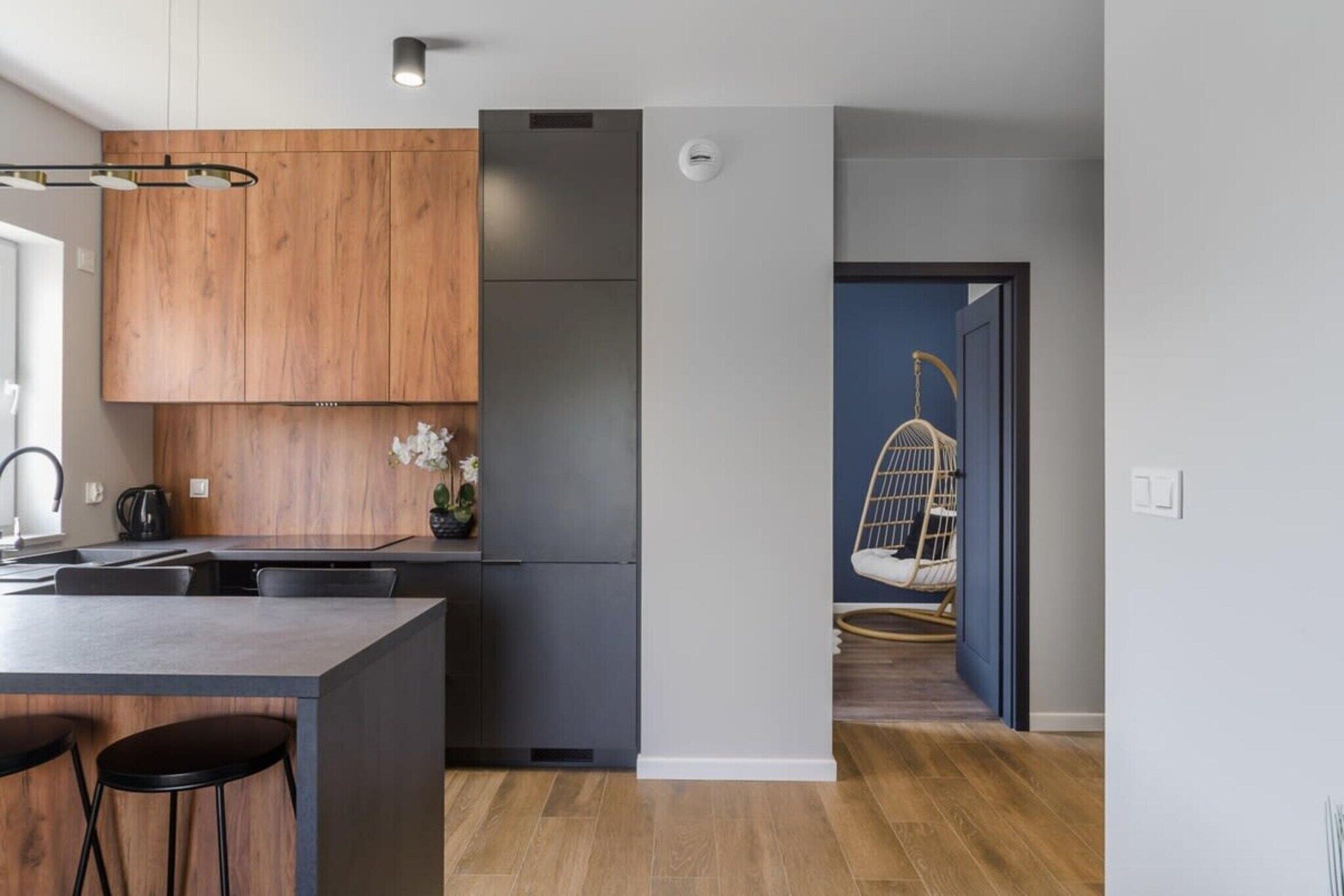 Una cocina moderna con armarios de madera, un refrigerador de acero inoxidable y una zona de bar con taburetes.