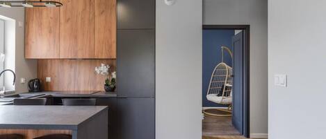 Una cocina moderna con armarios de madera, un refrigerador de acero inoxidable y una zona de bar con taburetes.
