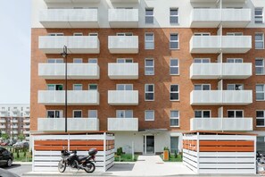 A multi-story residential building with balconies, a gated entrance, and a motorcycle parked in front. - Cozy City Retreat for 4 in Warsaw (Łódź)