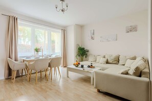 Ein modernes Wohnzimmer mit einer Couch, einem Esstisch, Stühlen und einem Couchtisch.