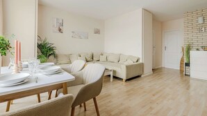 En moderne stue med sofa, spisebord med tallerkener og glas, en lysekrone og en murstensvæg.