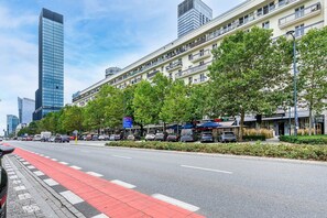 A street lined with trees and parked cars, with buildings in the background. - City View Apartment in Warsaw (Warszawa 2)