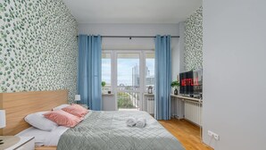Ein Hotelzimmer mit Bett, Fernseher und Blick auf die Stadt.