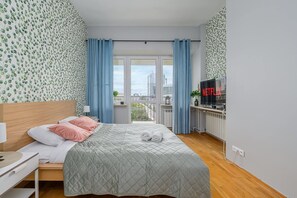 A hotel room with a bed, a TV, and a view of the city. - City View Apartment in Warsaw (Warszawa 2)