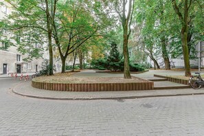 Ein gepflasterter Fußweg mit Bäumen, einem Fahrrad und einem Gebäude im Hintergrund.