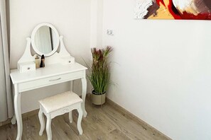 A white vanity with a mirror, a bench, and a potted plant. - Lodz Apartment for 4 Guests (Łódź)