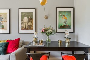 Ein Essbereich mit einem dunklen Holztisch, Stühlen, einer Vase mit Blumen und gerahmten Bildern an der Wand.